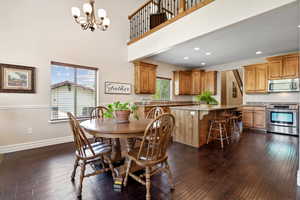 Dining space featuring dark wood-style flooring, baseboards, an inviting chandelier, and a healthy amount of sunlight