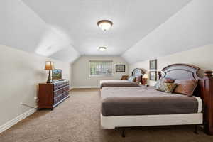 Carpeted bedroom featuring baseboards and vaulted ceiling