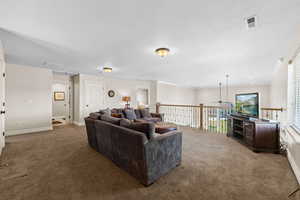 Carpeted living area featuring visible vents, baseboards, and ceiling fan