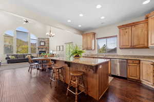 Kitchen with stainless steel dishwasher, a fireplace, a kitchen bar, light stone counters, and open floor plan