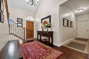 Entrance foyer featuring wood-type flooring, baseboards, a chandelier, and stairs