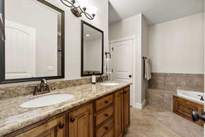 Full bathroom with a tub, double vanity, a sink, and tile patterned flooring