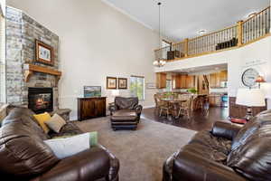 Living area featuring a high ceiling, baseboards, dark wood-style floors, and a stone fireplace