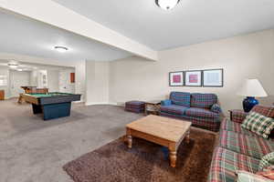 Carpeted living room featuring baseboards, visible vents, pool table, and beam ceiling