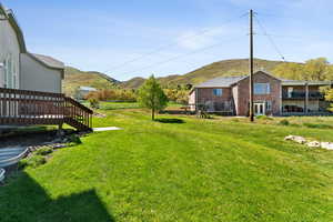 View of yard with a deck with mountain view, a playground, and fence