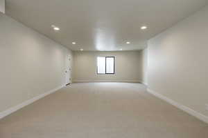 Empty room with light colored carpet, recessed lighting, and a textured ceiling