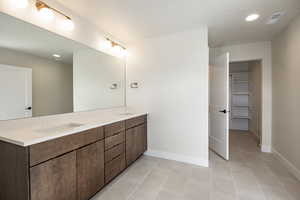 Bathroom featuring a walk in closet, double vanity, recessed lighting, light tile patterned floors, and a textured ceiling