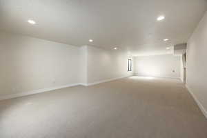 Spare room featuring light carpet, a textured ceiling, and recessed lighting