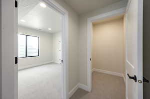 Corridor featuring light colored carpet, recessed lighting, and a textured ceiling
