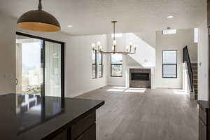 Unfurnished living room with light wood-style flooring, a premium fireplace, a textured ceiling, a chandelier, and recessed lighting