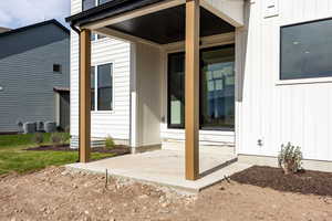 View of exterior entry with board and batten siding and a patio area