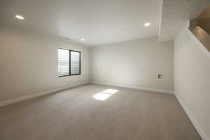 Additional living space with light colored carpet, a textured ceiling, and recessed lighting