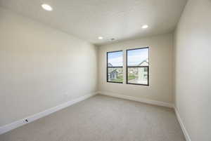 Empty room featuring light colored carpet, recessed lighting, and a textured ceiling