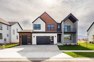 Modern farmhouse style home featuring a balcony, driveway, a front lawn, and a garage