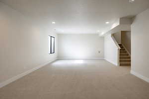 Unfurnished room with light carpet, stairs, recessed lighting, and a textured ceiling