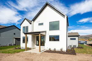 Rear view of house with a patio area, a lawn, board and batten siding, and a mountain view