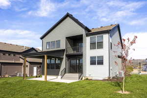 Back of house featuring a balcony, a patio area, and a yard