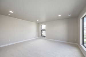 Empty room with light colored carpet and recessed lighting