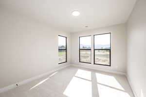 Empty room featuring light colored carpet and a mountain view
