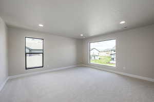 Empty room with light colored carpet, plenty of natural light, recessed lighting, and a textured ceiling