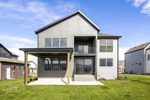 Rear view of house featuring a balcony, a lawn, a patio, and entry steps