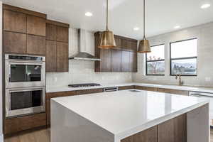 Kitchen featuring stainless steel appliances, modern cabinets, backsplash, light stone counters, and recessed lighting