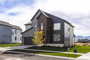 View of front of house with a front yard, concrete driveway, a garage, and a mountain view