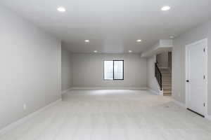 Unfurnished room featuring light carpet, stairs, and recessed lighting