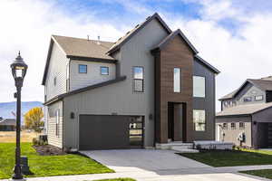 View of front of house with a front lawn, concrete driveway, and an attached garage