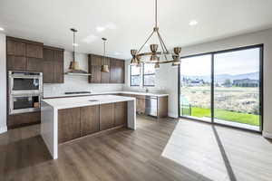 Kitchen featuring a mountain view, appliances with stainless steel finishes, backsplash, wall chimney exhaust hood, and dark wood-type flooring