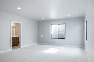 Unfurnished bedroom featuring light carpet, recessed lighting, and connected bathroom
