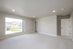 Spare room with light carpet, recessed lighting, a mountain view, and a textured ceiling