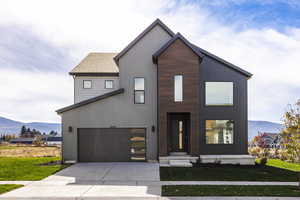 View of front of property with a mountain view, a front lawn, concrete driveway, and an attached garage