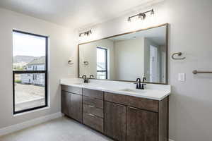 Full bathroom featuring plenty of natural light, double vanity, light tile patterned floors, and a textured ceiling