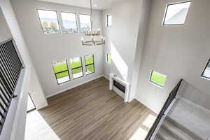 Unfurnished living room featuring a high ceiling, stairs, light wood-type flooring, a chandelier, and a glass covered fireplace