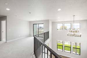 Hall featuring a textured ceiling, recessed lighting, a chandelier, light colored carpet, and an upstairs landing