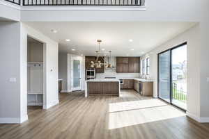 Kitchen featuring decorative light fixtures, decorative backsplash, light wood-style flooring, a center island, and modern cabinets