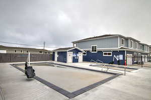 Rear view of property featuring a community pool, a patio area, and fence