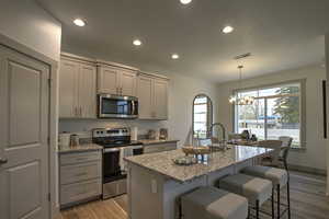 Kitchen with appliances with stainless steel finishes, light wood finished floors, recessed lighting, gray cabinetry, and light stone countertops