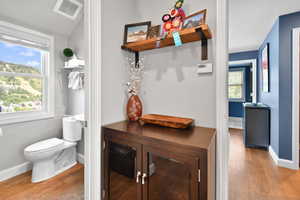 Bathroom with toilet, wood finished floors, baseboards, and visible vents