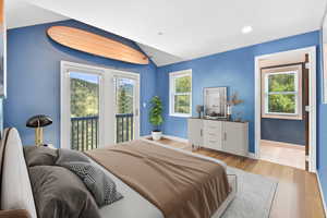 Bedroom featuring access to exterior, light wood finished floors, baseboards, and lofted ceiling