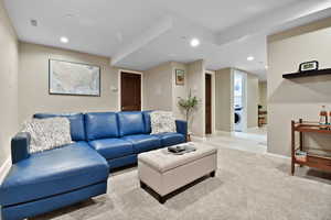 Living room with visible vents, baseboards, recessed lighting, washer / dryer, and light colored carpet