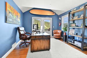 Home office with french doors, baseboards, wood finished floors, and lofted ceiling