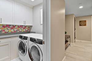 Washroom with cabinet space, washer and clothes dryer, recessed lighting, and baseboards