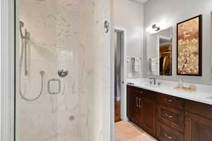 Bathroom featuring marble finish floor, a sink, a walk in closet, a marble finish shower, and double vanity