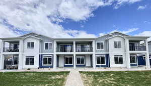 View of front of house featuring board and batten siding, a front yard, and a balcony