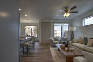Living room featuring visible vents, recessed lighting, wood finished floors, and ceiling fan with notable chandelier
