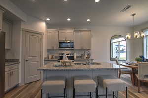 Kitchen with stainless steel appliances, visible vents, a breakfast bar, and a sink