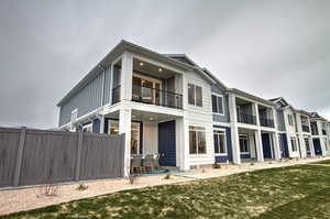 Back of house with board and batten siding, a yard, and fence