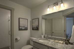 Bathroom featuring a shower stall, vanity, baseboards, and toilet